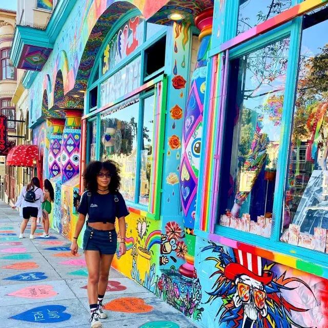 Woman walking down Haight Street with a colorful mural in the background.